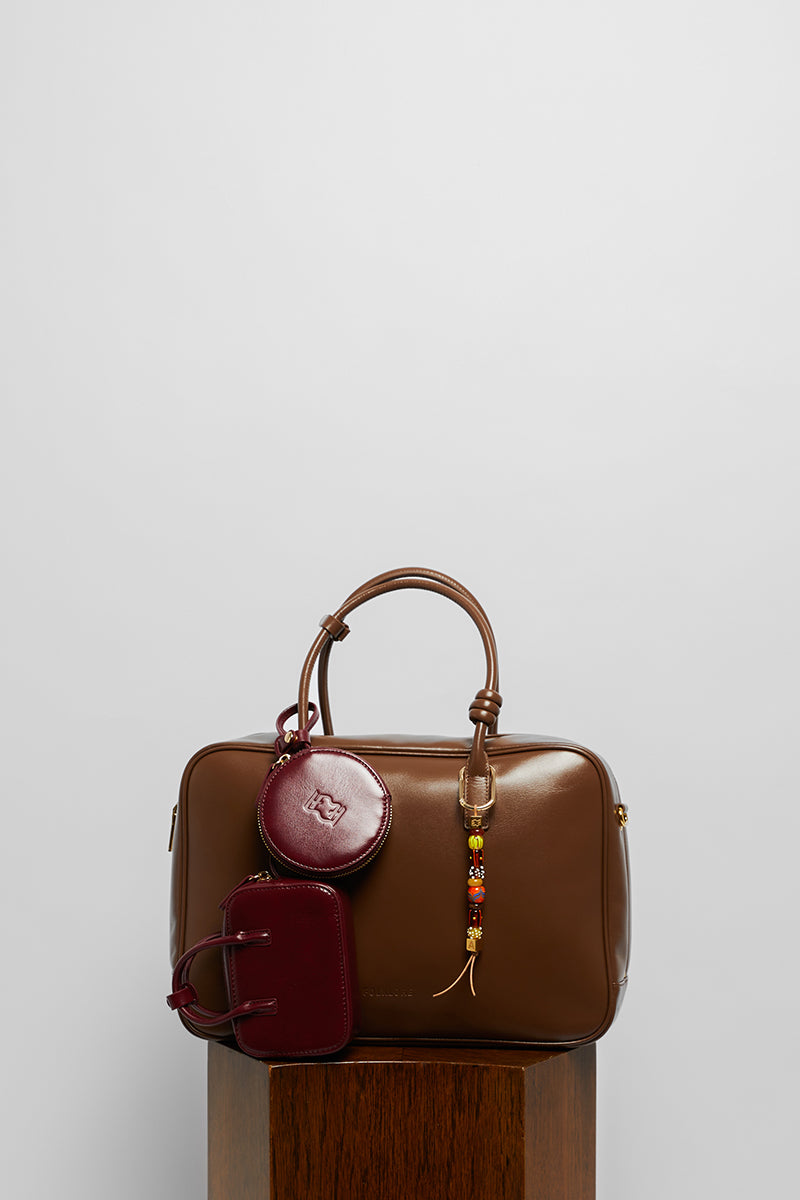 Leather work bag in mocha color with top handle, by Folklore The Label, shown with its sleek, structured design and polished finish.