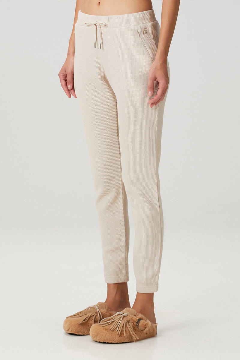 Beige waffle sweatpants by Bassigue featuring a relaxed fit and textured fabric, shown on a model.