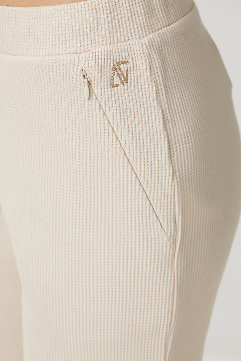 Beige waffle sweatpants by Bassigue, casual pants with textured waffle fabric and a relaxed fit, shown on a model.