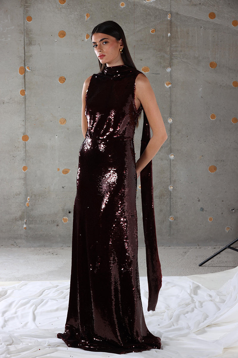 A brown Eclipse maxi dress by Aquarel Studio featuring a flowing silhouette and elegant design, displayed on a hanger.