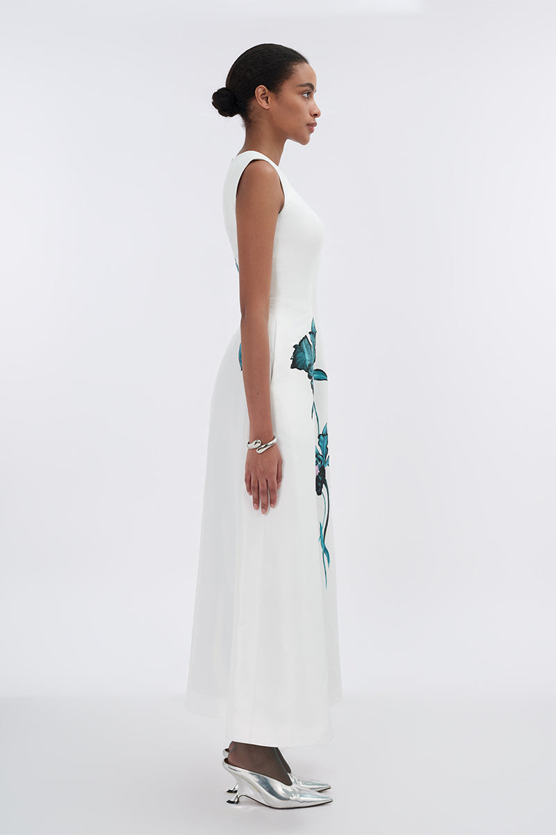 White asymmetrical flared maxi dress by Tiny Ink, flowing fabric with unique hem design, perfect for elegant summer occasions.