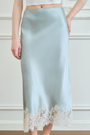 Green Windy Women's Silk Midi Skirt by Manito displayed on a hanger, showcasing smooth silk fabric and elegant flow.