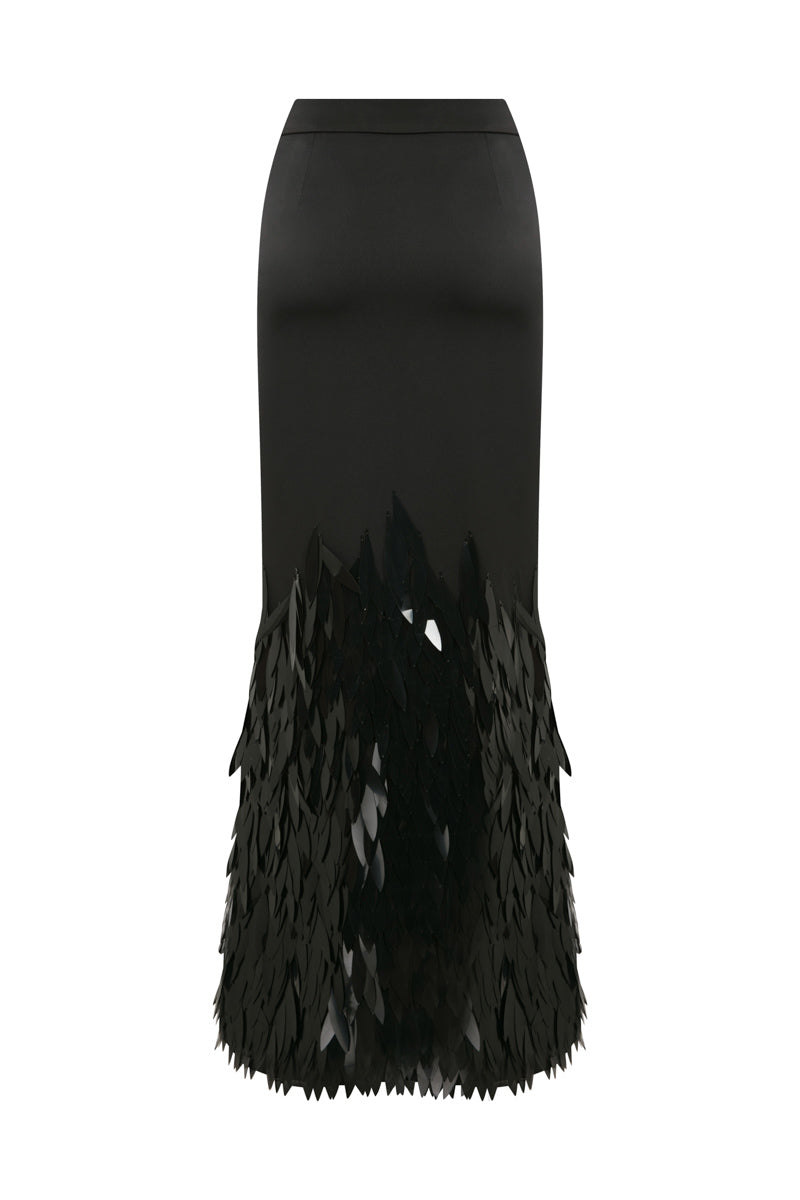 Black embellished mermaid maxi skirt by TAGG, featuring fitted waist and flowing fabric with decorative embellishments.