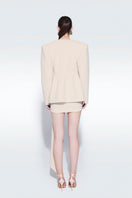 Beige draped mini skirt by Zeynep Tosun featuring flowing fabric and stylish design, shown on a model.