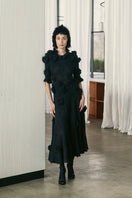 Black draped A-line maxi dress with floral details by Lalo, featuring elegant flowing fabric and floral accents.