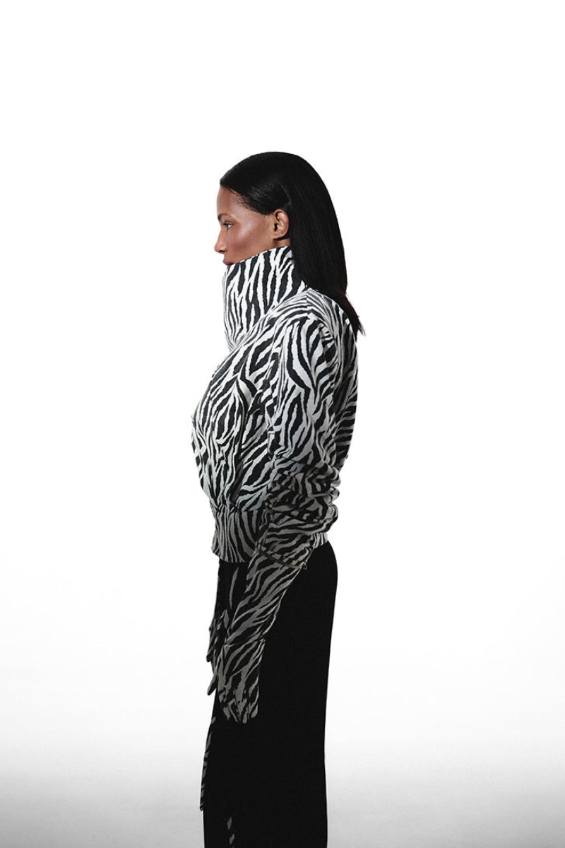 Black and white zebra print high neck bomber jacket with matching gloves by Kris Marán, shown from a side angle.