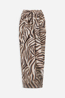 Zebra print cover-up pareo by Maliluha featuring a flowing fabric design, worn as a stylish beach or poolside accessory.