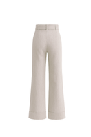 Light-colored ZIMA pants in sand from ANA + MARIA displayed on a ghostly background, showcasing relaxed fit and stylish design.