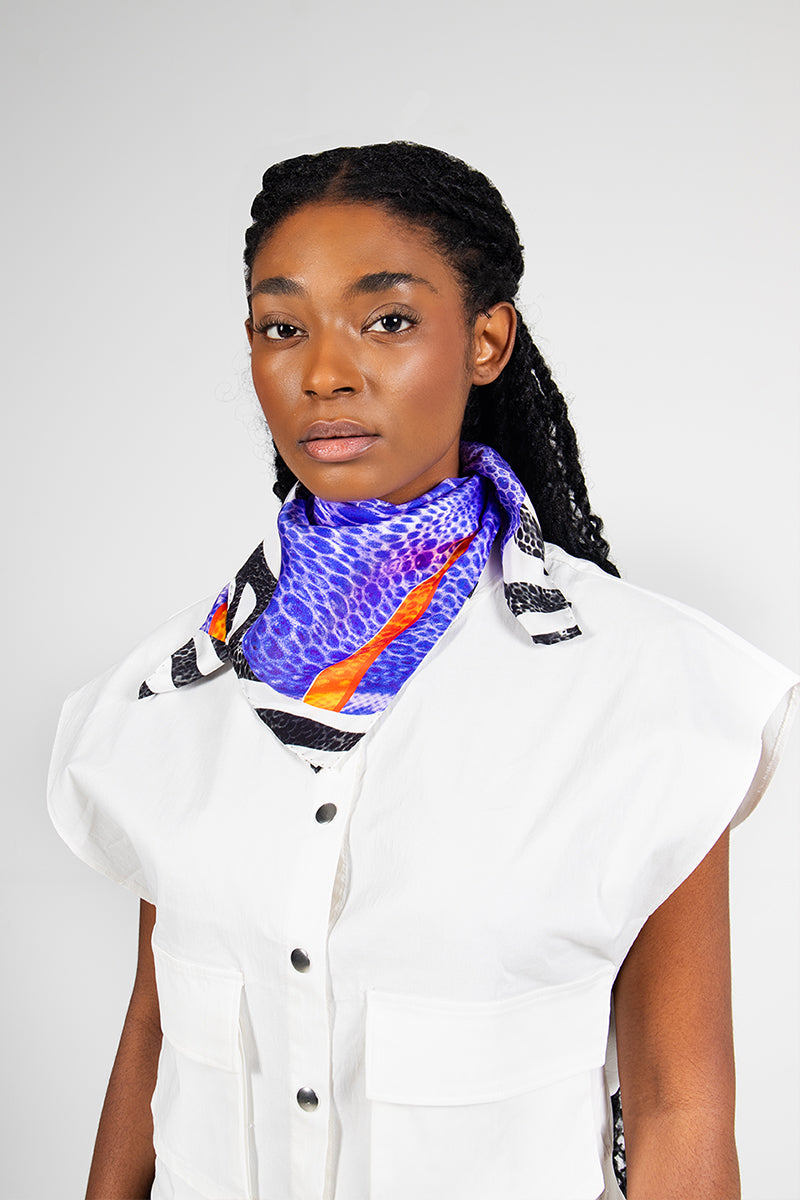 Amel Batita Zoo Moussard small silk scarf with vibrant animal print, styled around a neck for a chic look.