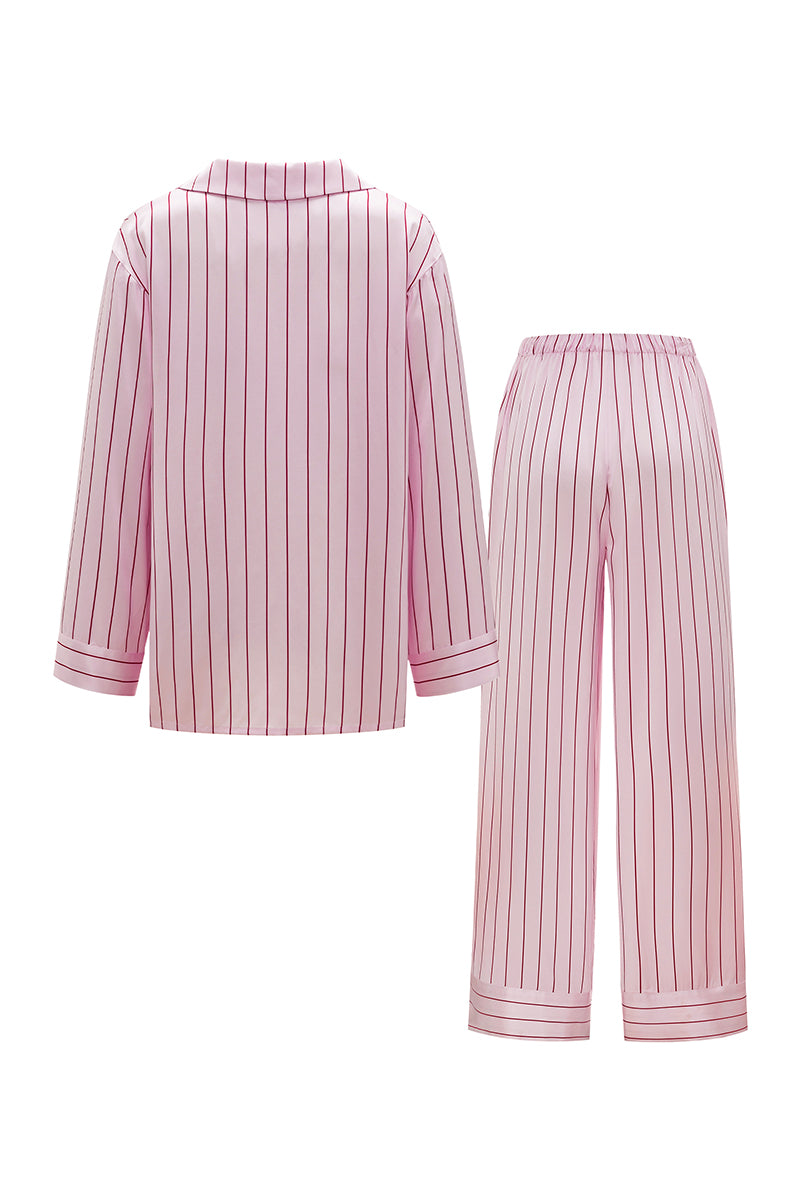 Pink striped silk pajama set by Not Just Pajama, featuring a long-sleeve top and matching pants from the Museum of Crush collection.