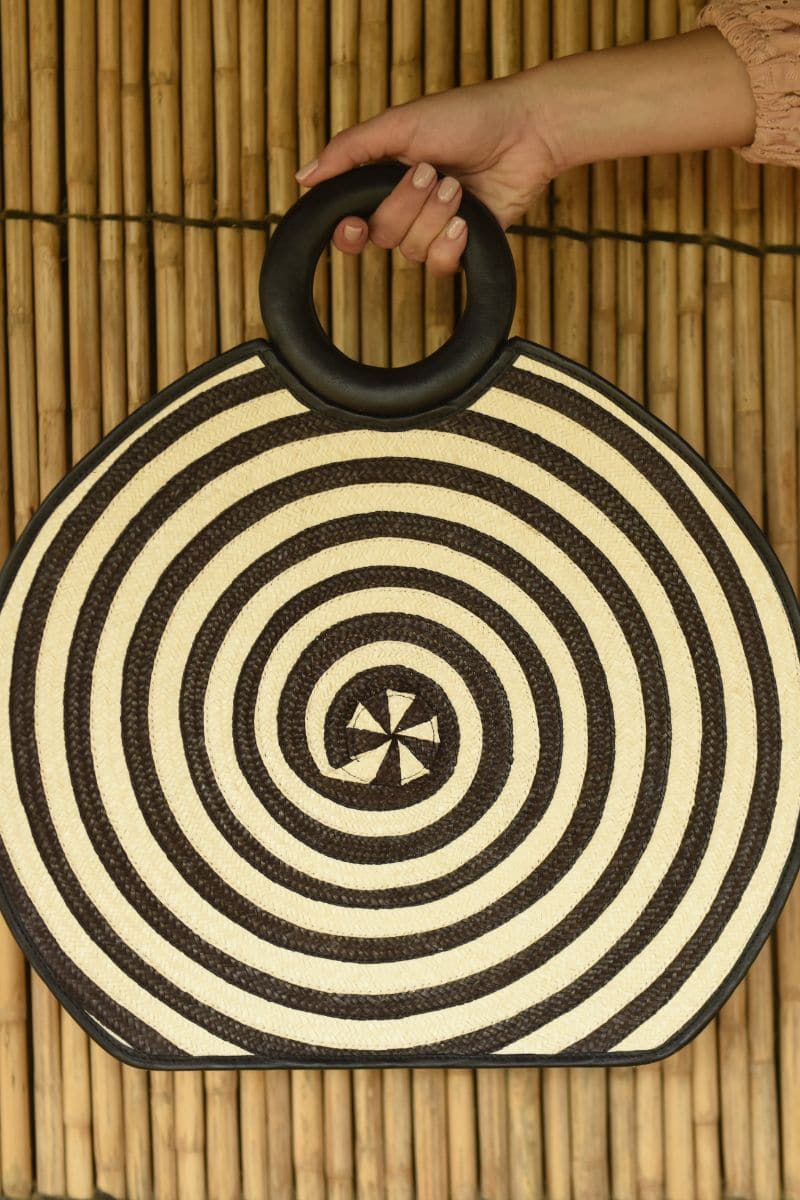 Black Zenú large leather and cana Flecha bag by Adriana Castro, featuring a top handle and woven design.
