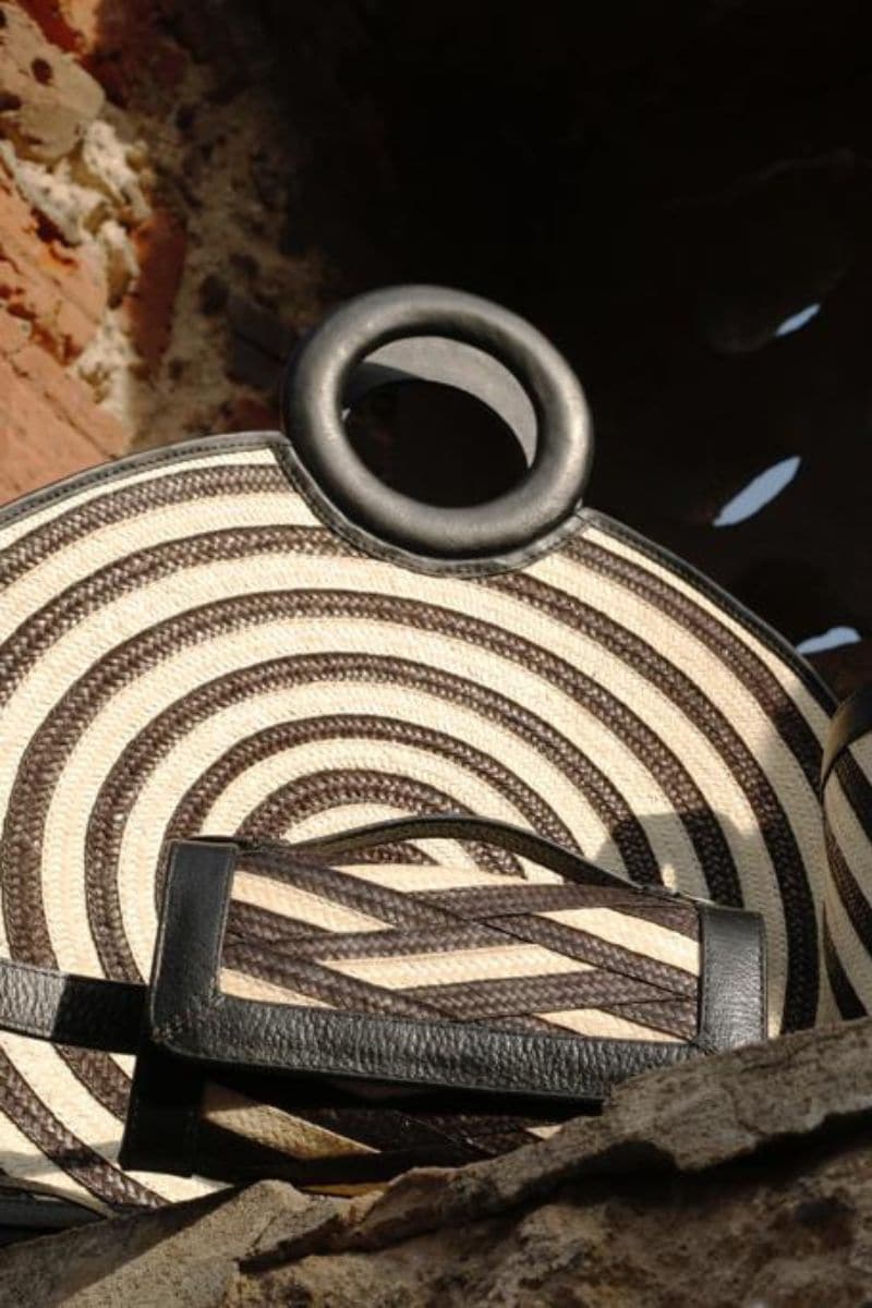 Black Zenú large leather and caña flecha bag by Adriana Castro, featuring a top handle and woven design.