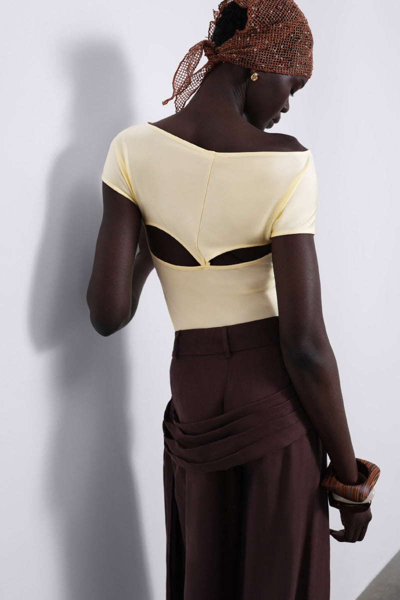 SÉLONE Aureon cut-out bodysuit in butter yellow, featuring stylish open shoulder design and fitted silhouette.