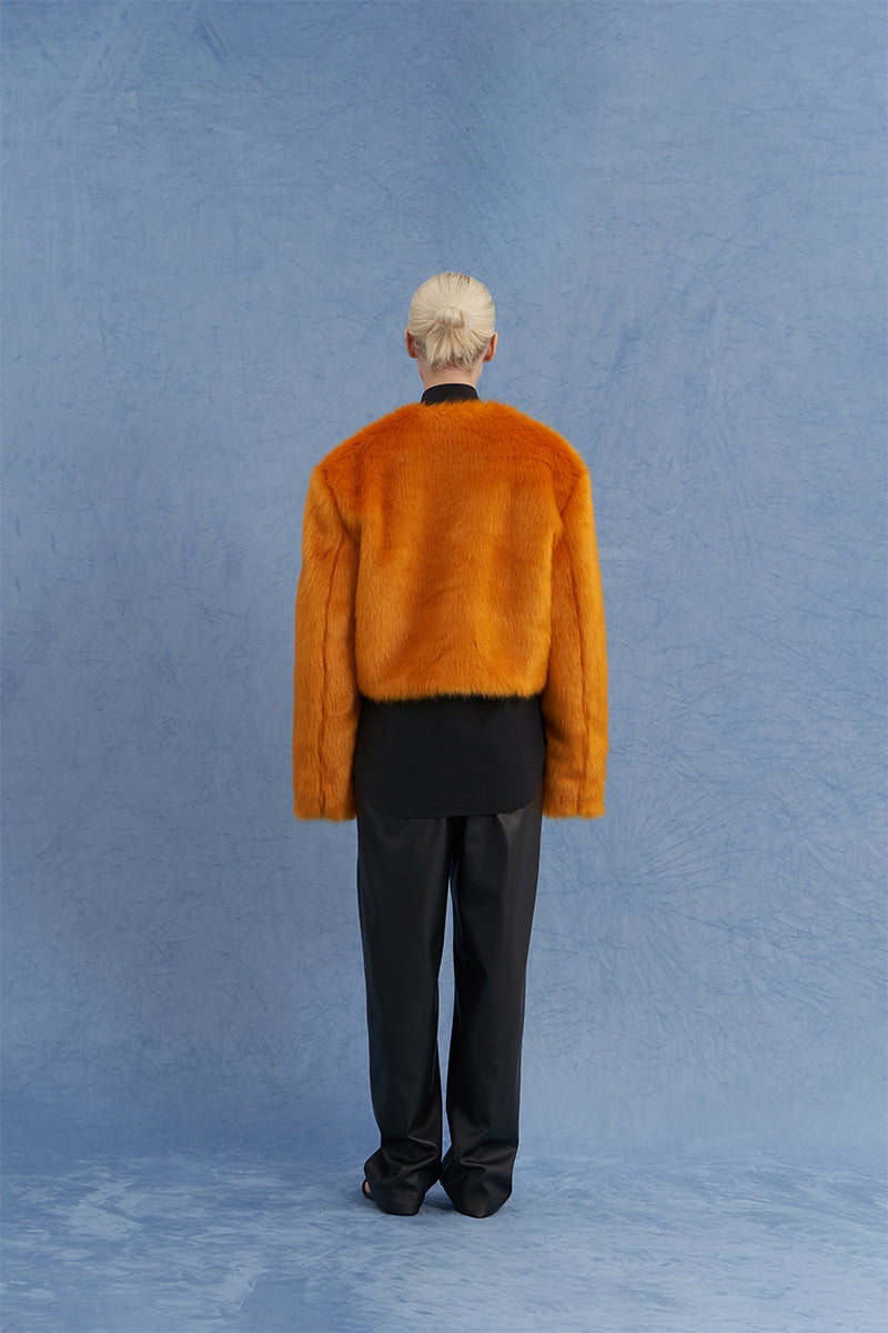 JINSUN exaggerated shoulder shearling jacket in orange, showing the back view with plush shearling details and stylish design.