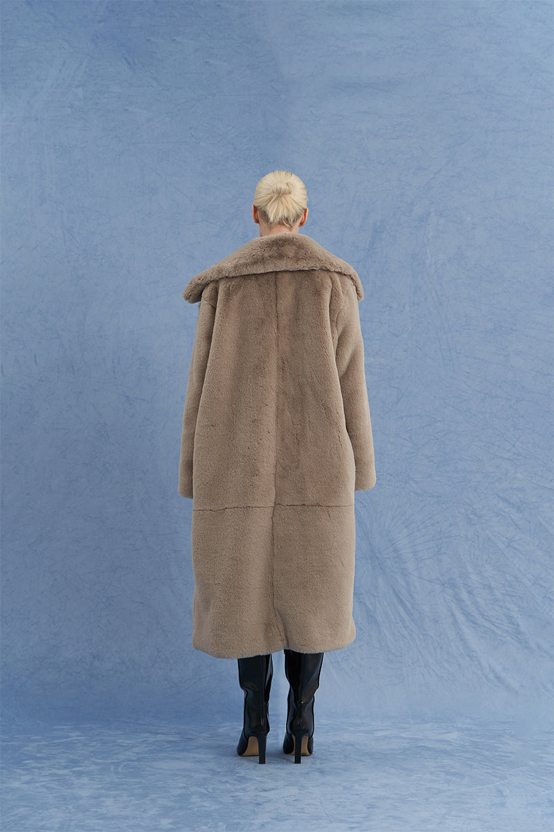 Brown oversized shearling coat by JINSUN shown from the back, featuring plush shearling material and relaxed fit style.