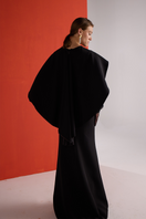 Back view of a black cascade gown by Joanna Andraos featuring flowing fabric and elegant draping.