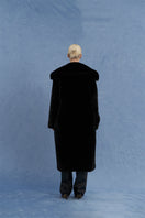 Black oversized shearling coat by JINSUN, shown from the back with plush shearling lining and wide collar detail.