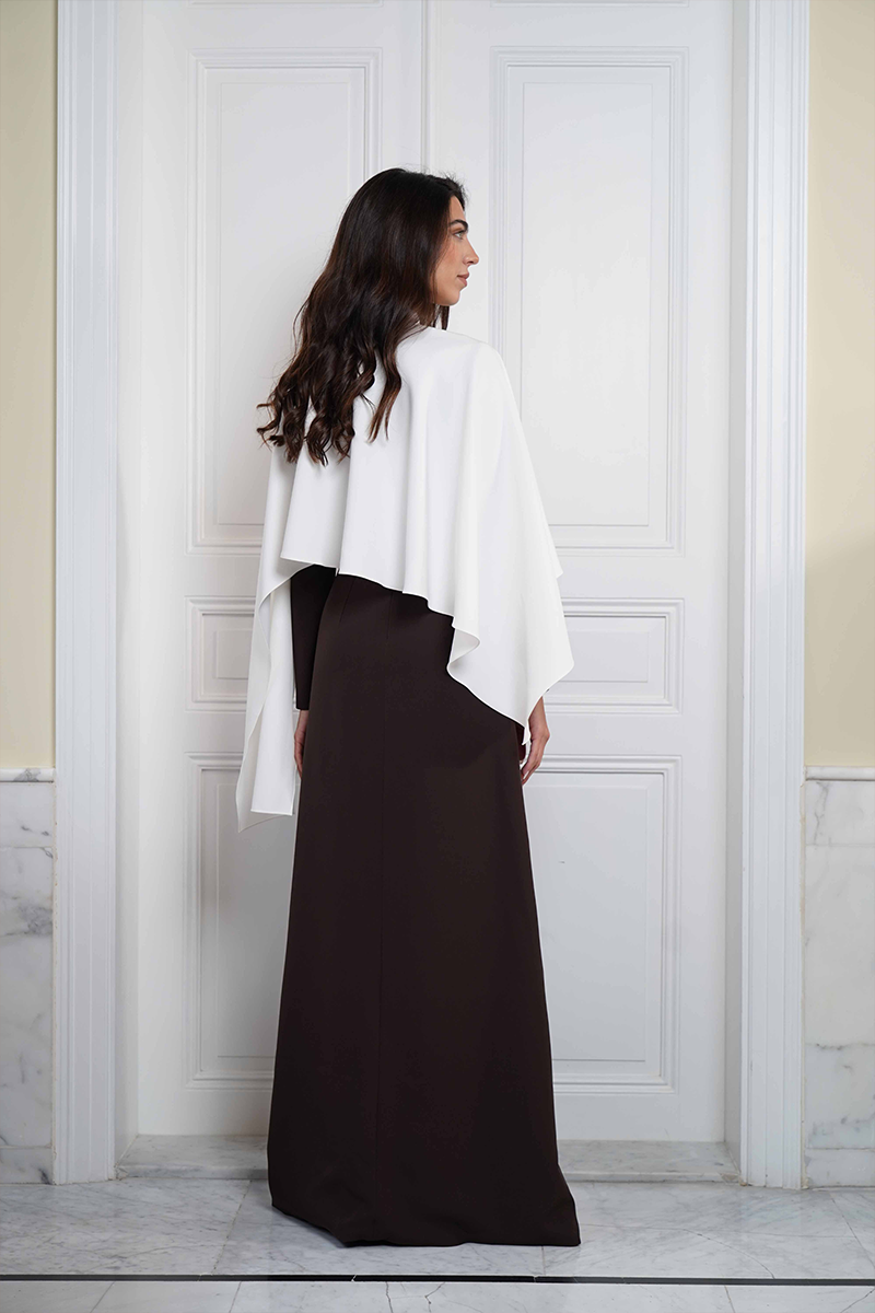 Joanna Andraos ivory cape evening gown shown from the back with flowing fabric and elegant design.