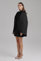 Black IRIS JET Cape jacket by BAÉ displayed on a model, showcasing its stylish design and sleek silhouette.