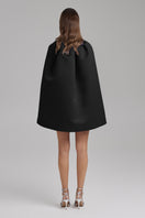Black IRIS JET Cape by BAÉ, stylish jacket with flowing fabric and sleek design, shown on a model in a fashion lookbook.