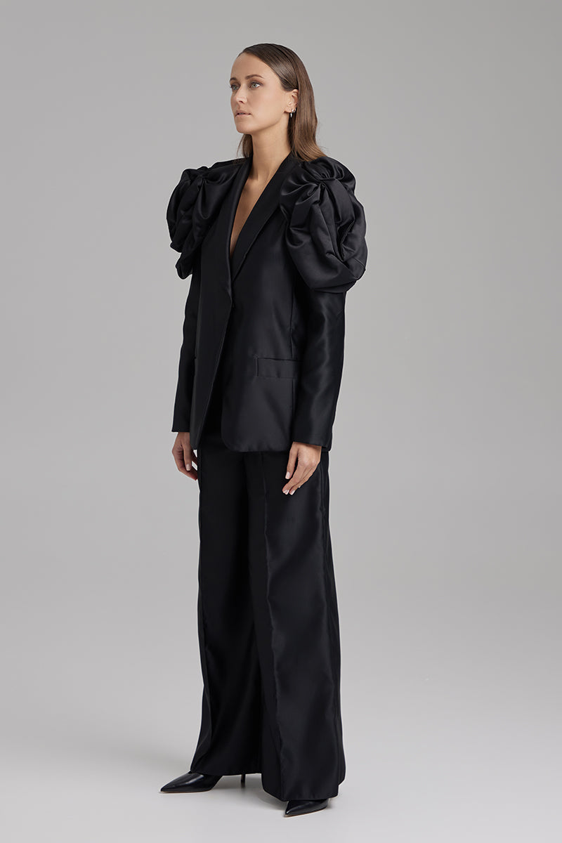 Black BAÉ ONYX Pants displayed on a model, showcasing a stylish, slim-fit design with a tailored waistband and sleek fabric.