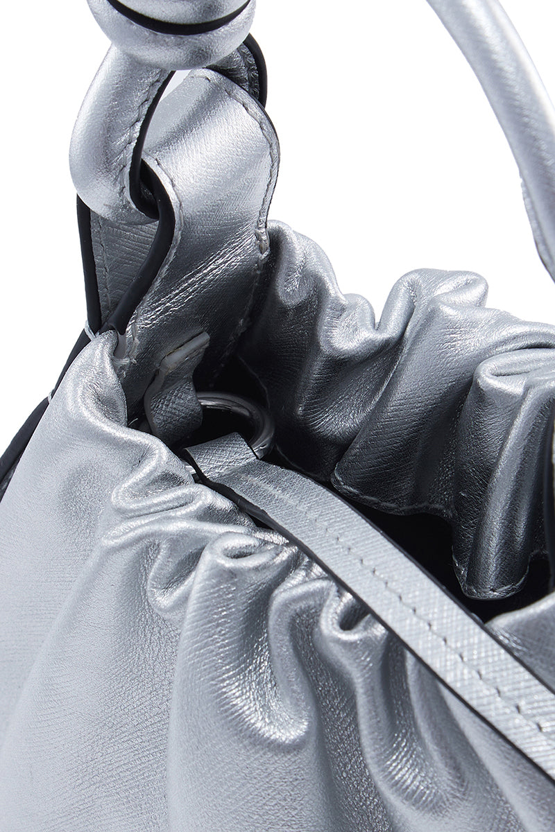 Silver Tina Baguette Mini metallic ruched Saffiano top handle bag by Behno New York with sleek design and textured finish.