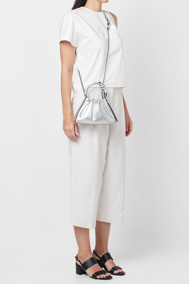 Silver metallic Baguette Mini top handle bag by behno New York with ruched saffiano leather, shown on body.