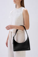 Black behno New York Danny Flatiron Bag Nappa shoulder bag worn on a model's arm, showcasing its sleek, minimal design.