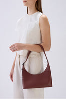 Behno New York Danny Flatiron Bag Nappa in brick color, shoulder bag style, shown on model's arms.