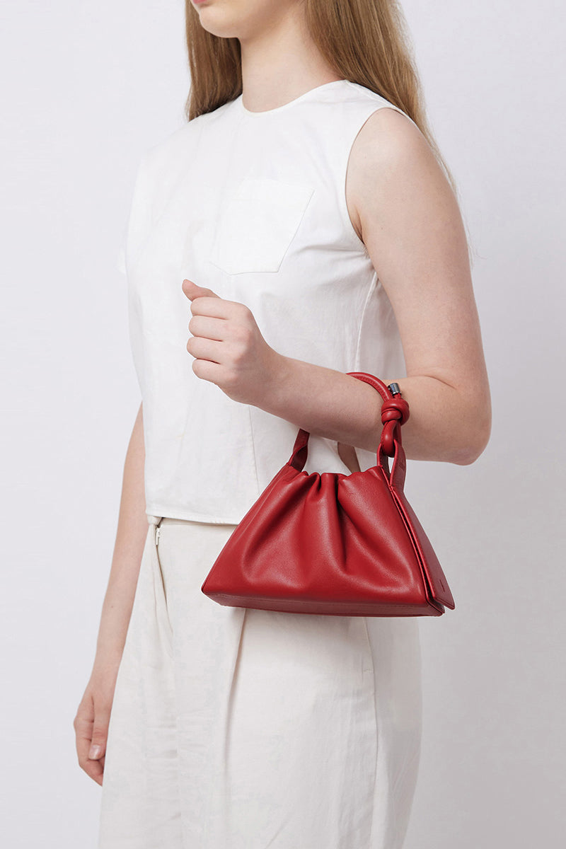 Red Behno New York Tina Baguette Mini Nappa Ruched top handle bag shown on model, highlighting its compact design and ruched details.