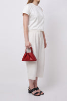Red Behno New York Tina Baguette Mini Nappa ruched top handle bag shown on model, featuring a sleek, compact design with ruched detailing.