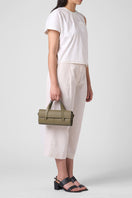 Behn0 New York Michelle Mini Crossbody Nappa Palm top handle bag shown on model, featuring smooth leather and compact design.