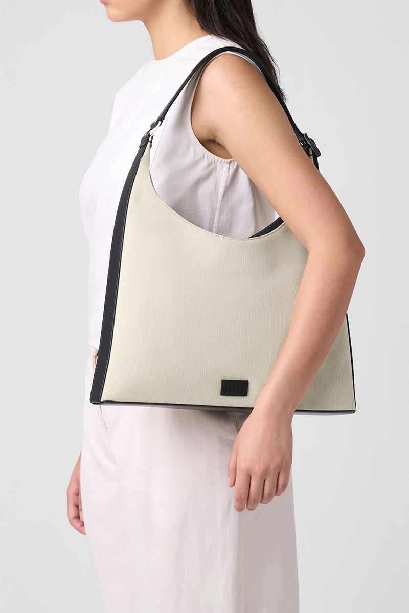Large canvas shoulder bag by behno New York in sand and black, shown on model with shoulder strap and spacious interior.