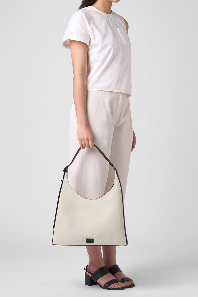 Large canvas shoulder bag by behno New York in sand and black, shown on model, featuring a spacious design and sturdy shoulder strap.