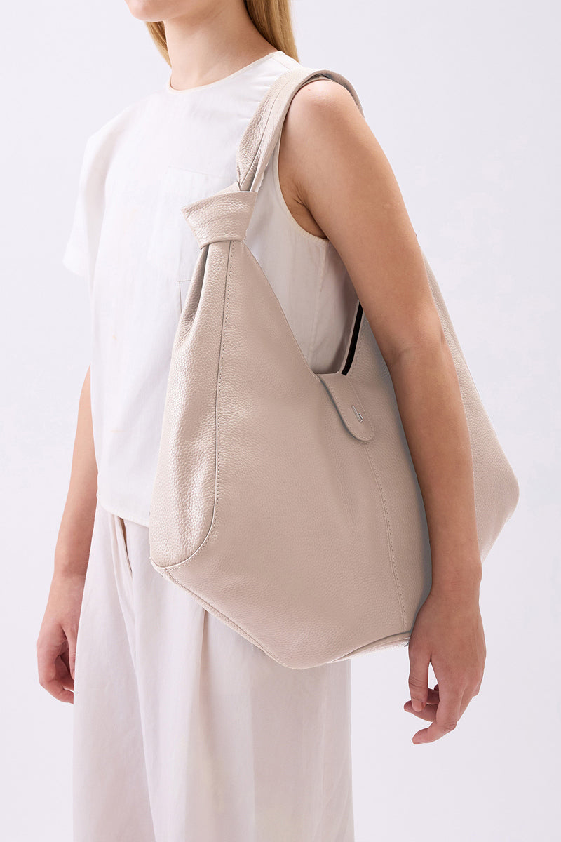 Behnо New York Nelli Hobo large pebble shoulder bag in bone color, shown on model with strap over shoulder and side view.