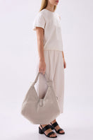 Large NELLI HOBO pebble leather shoulder bag in bone color by behno New York, shown on model.