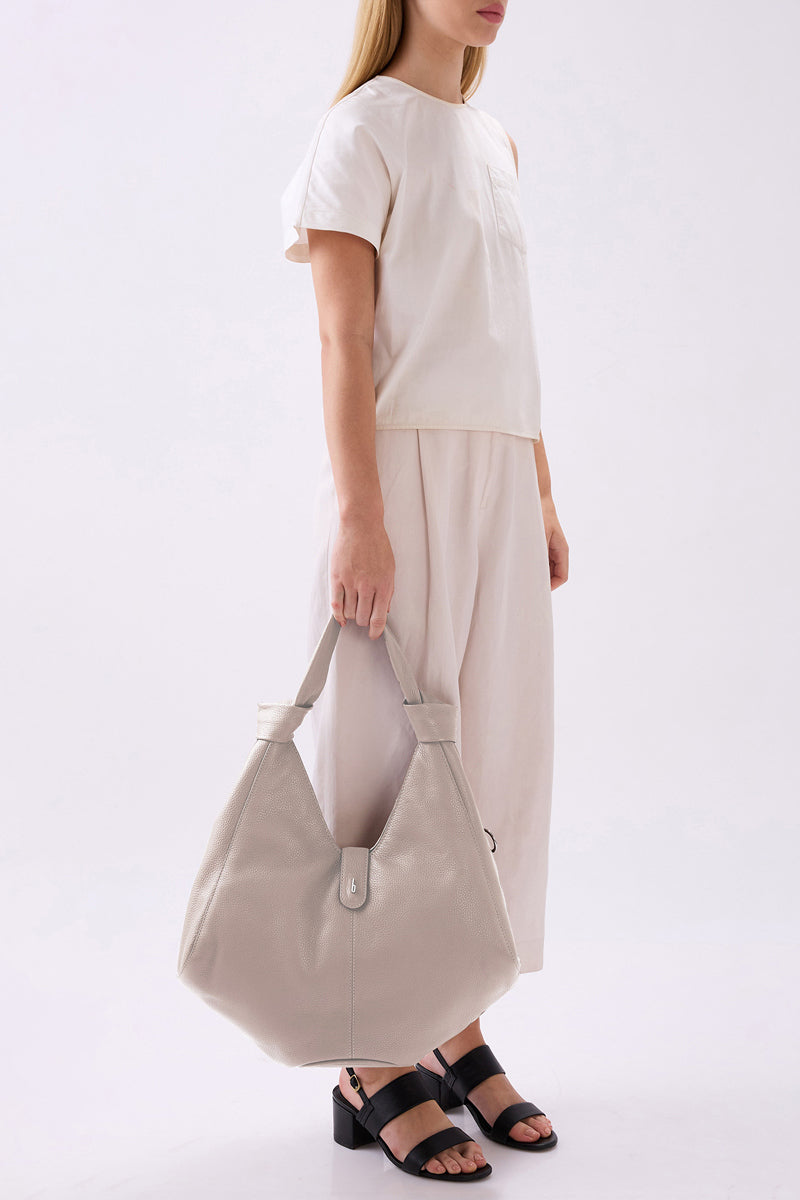 Large NELLI HOBO pebble leather shoulder bag in bone color by behno New York, shown on model.