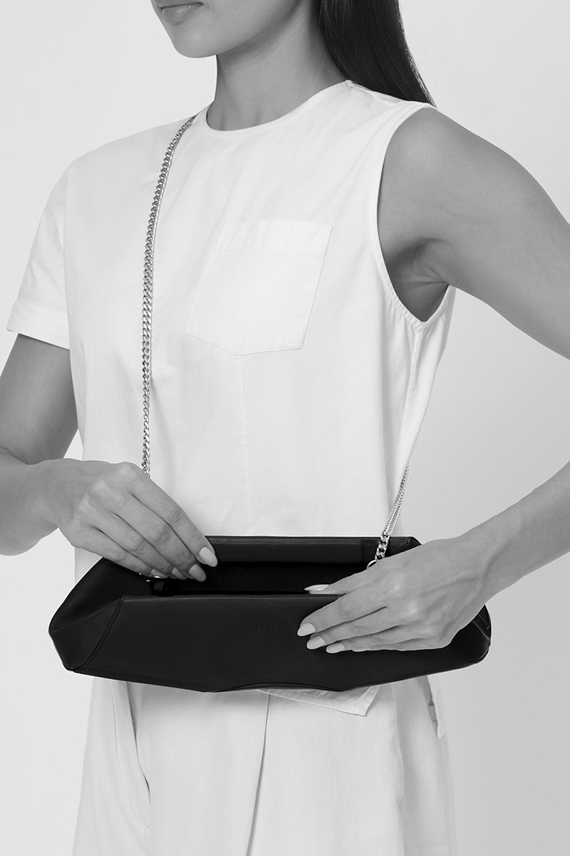 Behnio New York Elizabeth Baguette Mini Clutch in hematite with sleek, metallic finish and compact design, shown on body.