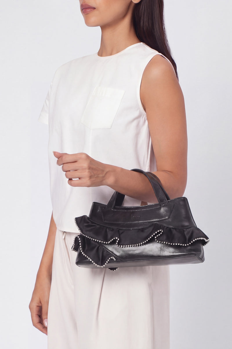 Black silk Franca Bag by behno New York with ruffle detail, top handle design, and crinkled texture, shown on model.