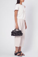 Black Behno New York Franca Bag with silk ruffle detail, top handle design, and crinkle texture, showcased on model.