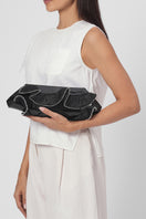 Black Elizabeth Baguette Mini Clutch by behno New York with ruffle silk and crinkle design, casual on-body shot.