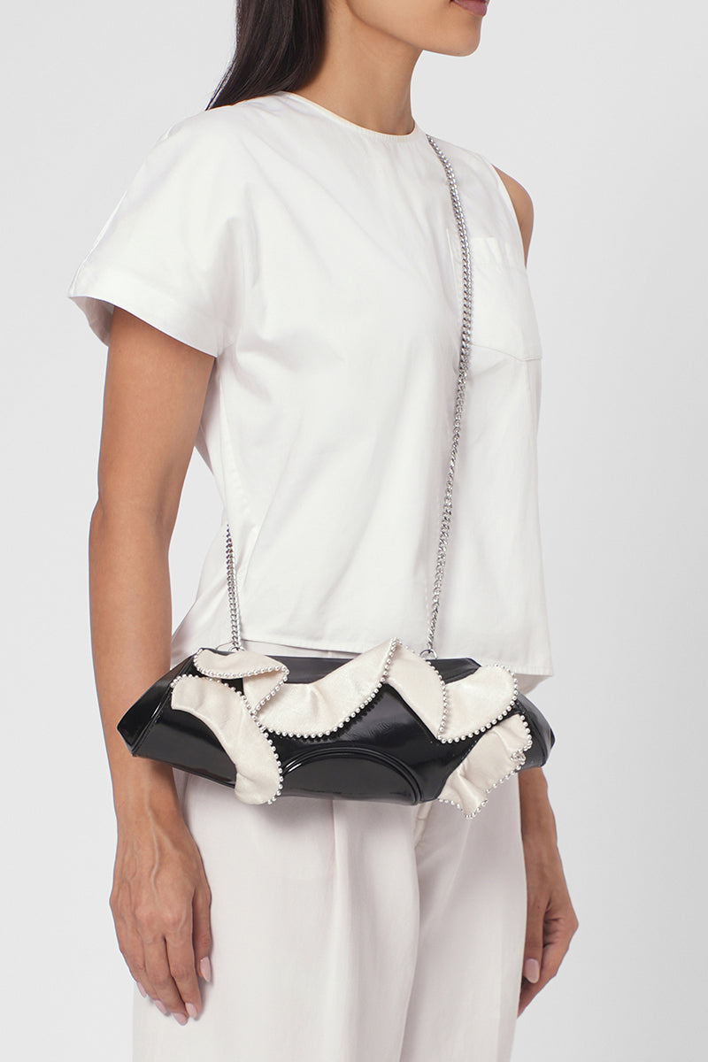 Behnó New York Elizabeth Baguette Mini Clutch in crinkled silk with ruffle details, in pumice and black colors, on body shot.