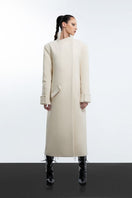 Milky white long coat by Blikvanger, shown on a mannequin, featuring a sleek design and full-length style.
