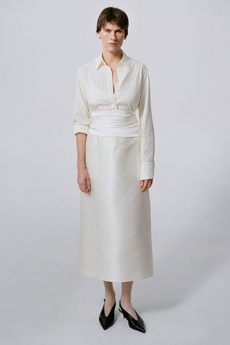 DELEGAN velvet blush silk midi skirt displayed in a fashion campaign image with flowing fabric and elegant design.