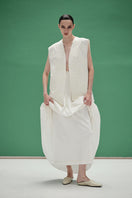 White maxi skirt with hand-embroidered tie from DELEGAN, featuring flowing fabric and elegant design.