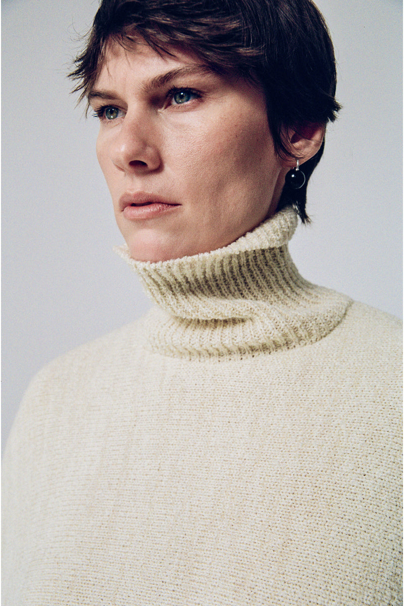 DELEGAN milk blush cardigan poncho, soft knit fabric, draped style, in a light blush color, displayed on a model for a fashion campaign