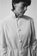 Ivory velvet coat by Delegan, stylish long coat with plush velvet fabric, shown hanging against a neutral background.