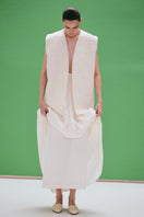 White maxi skirt with hand-embroidered tie detail from DELEGAN, featuring flowing fabric and elegant design.