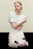 White short sleeve bodysuit from DELEGAN, displayed on a model, showcasing its fitted design and smooth fabric.