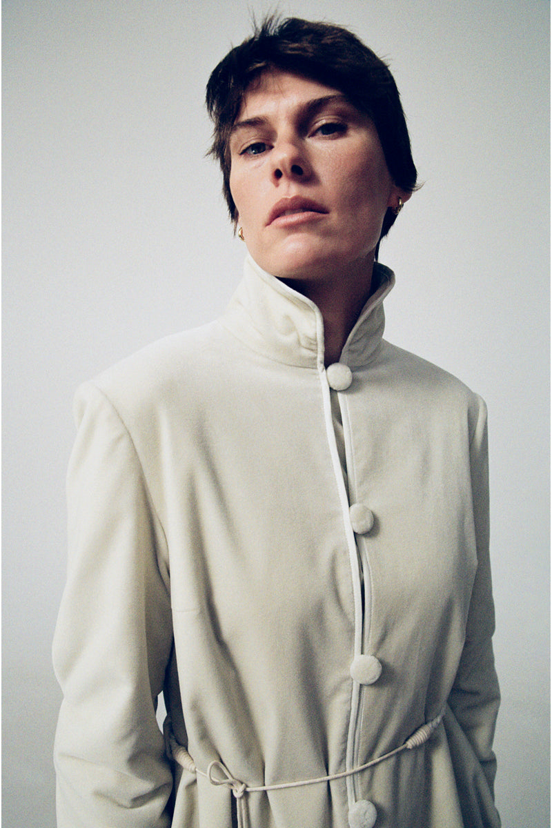 Elegant ivory velvet coat by Delegan featuring a tailored fit and luxurious fabric, shown on a model in a fashion campaign photo.
